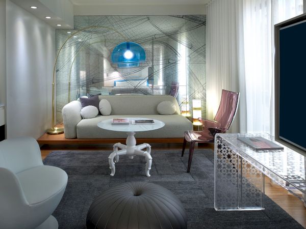 A modern, stylish living room with a white sofa, mirrored wall, blue pendant light, round coffee table, and a knitted ottoman in front of a glass desk and large window.