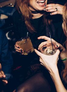 People partying and holding drinks; a close-up of hands, cups, and a bite of food.