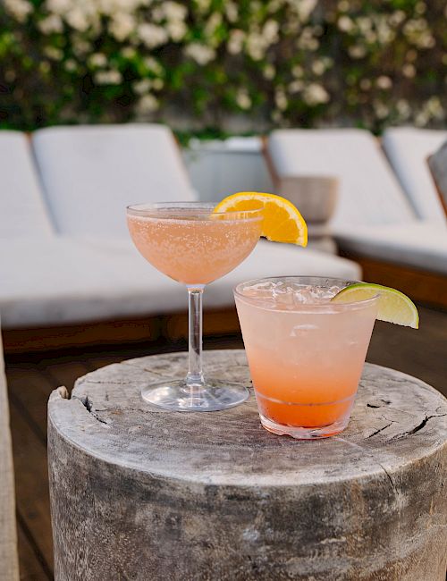 Two cocktails on a table next to a lounge.