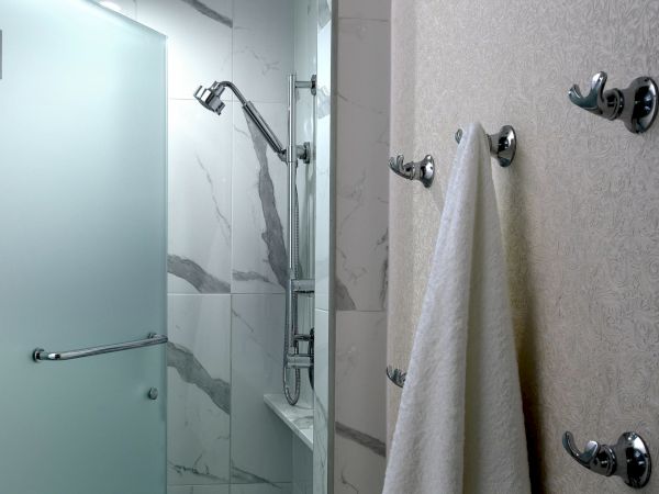 A modern bathroom shower with chrome faucet, handheld sprayer, and white tiled walls with a patterned curtain.